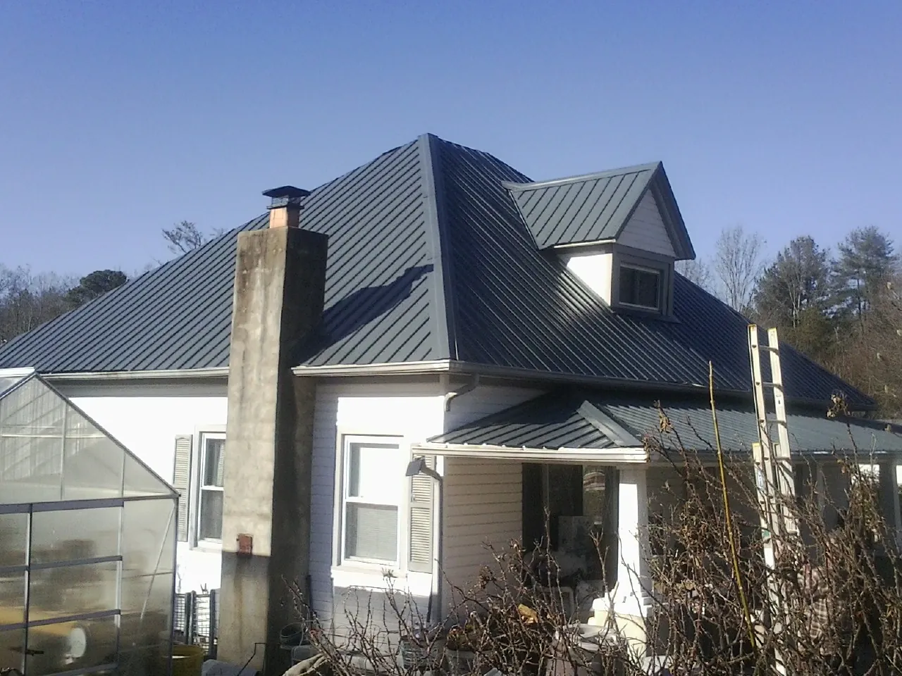 Dark blue standing seam metal roof on a white farmhouse with dormer — Slate & Tile Roof Repair by Roofing Brothers in Mosier