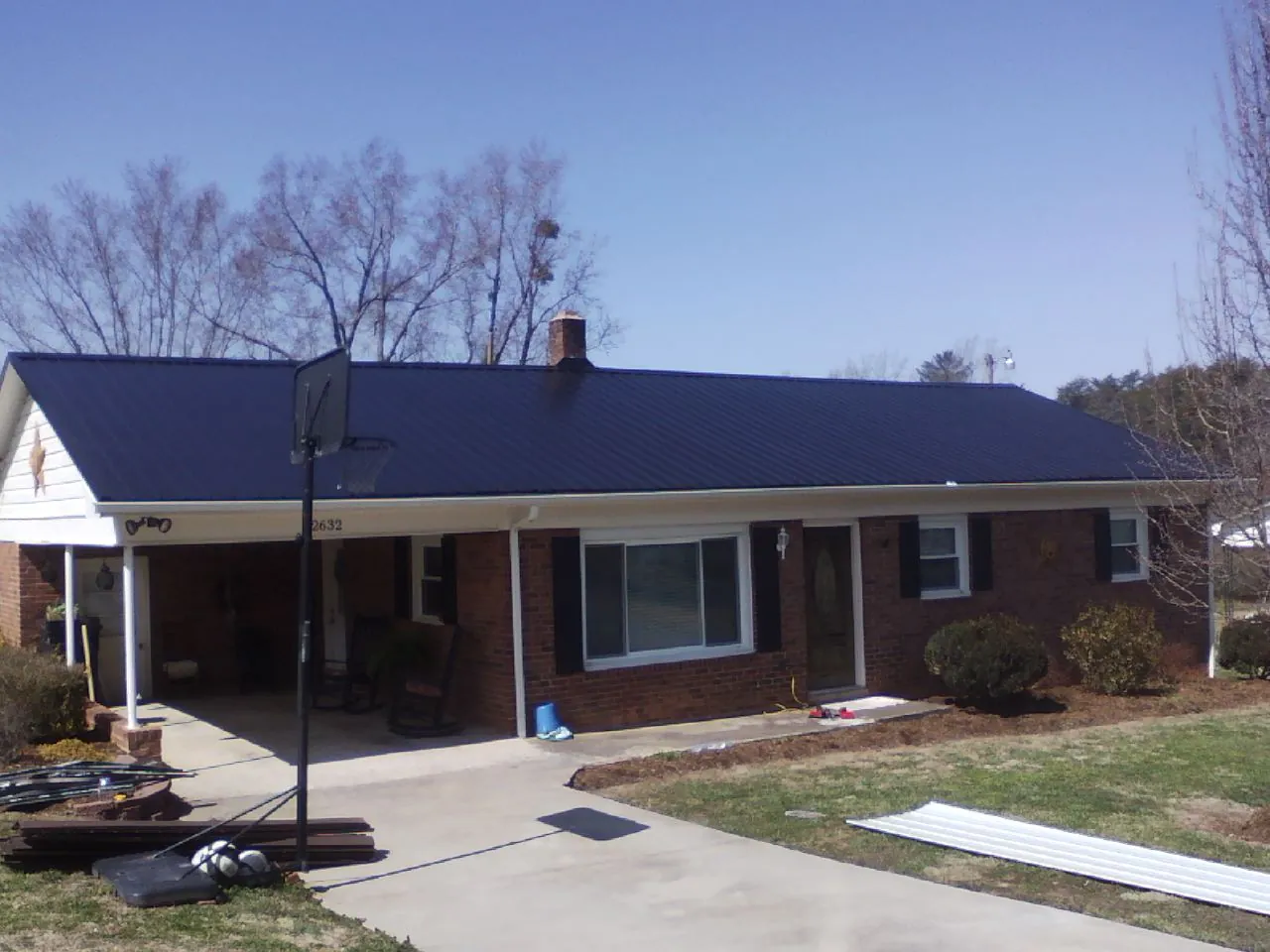 Finished dark blue metal roof on a brick ranch with a carport in Mosier