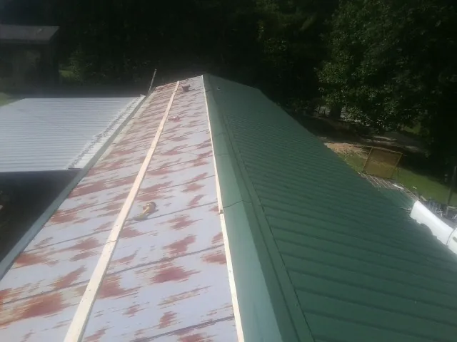 Old rusted panels beside newly installed green metal roofing — Wind Damage Roof Repair by Roofing Brothers in Mosier
