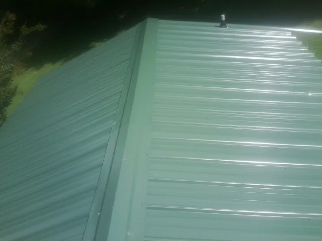 New green metal panels meeting at the ridge of a roof — Flat Roof Repair work by our crew in Mosier