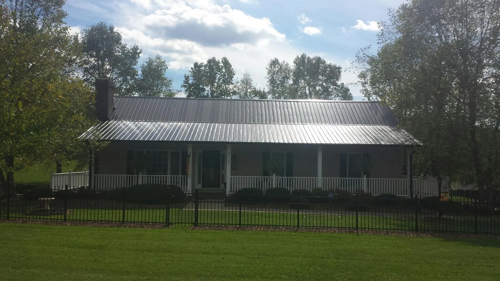Gray metal roof on a brick ranch with a full width front porch — Gutter Guard Installation work by our crew in Mosier