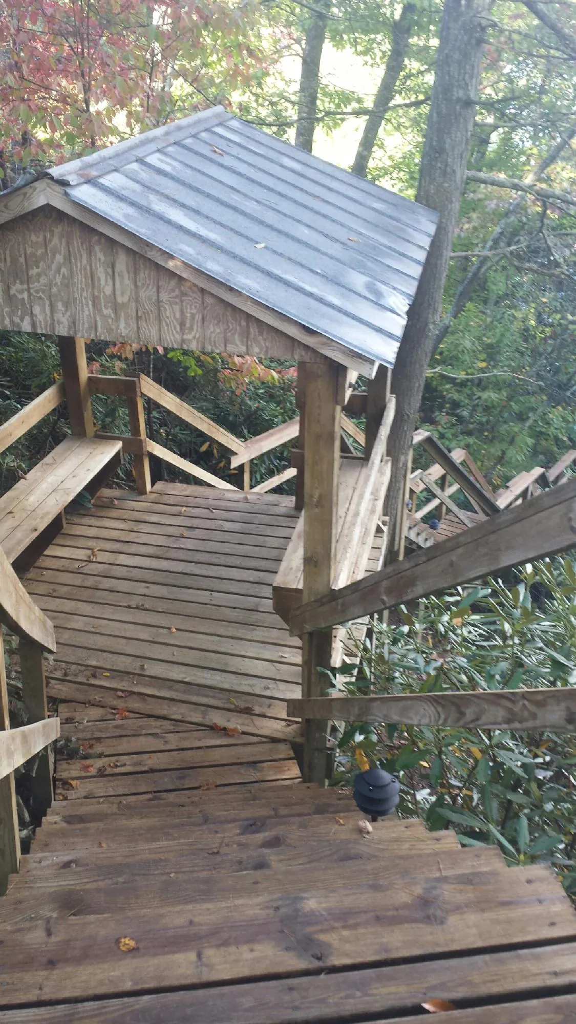 Metal roofed shelter over wooden steps on a wooded walkway — Skylight Repair & Installation work by our crew in Mosier