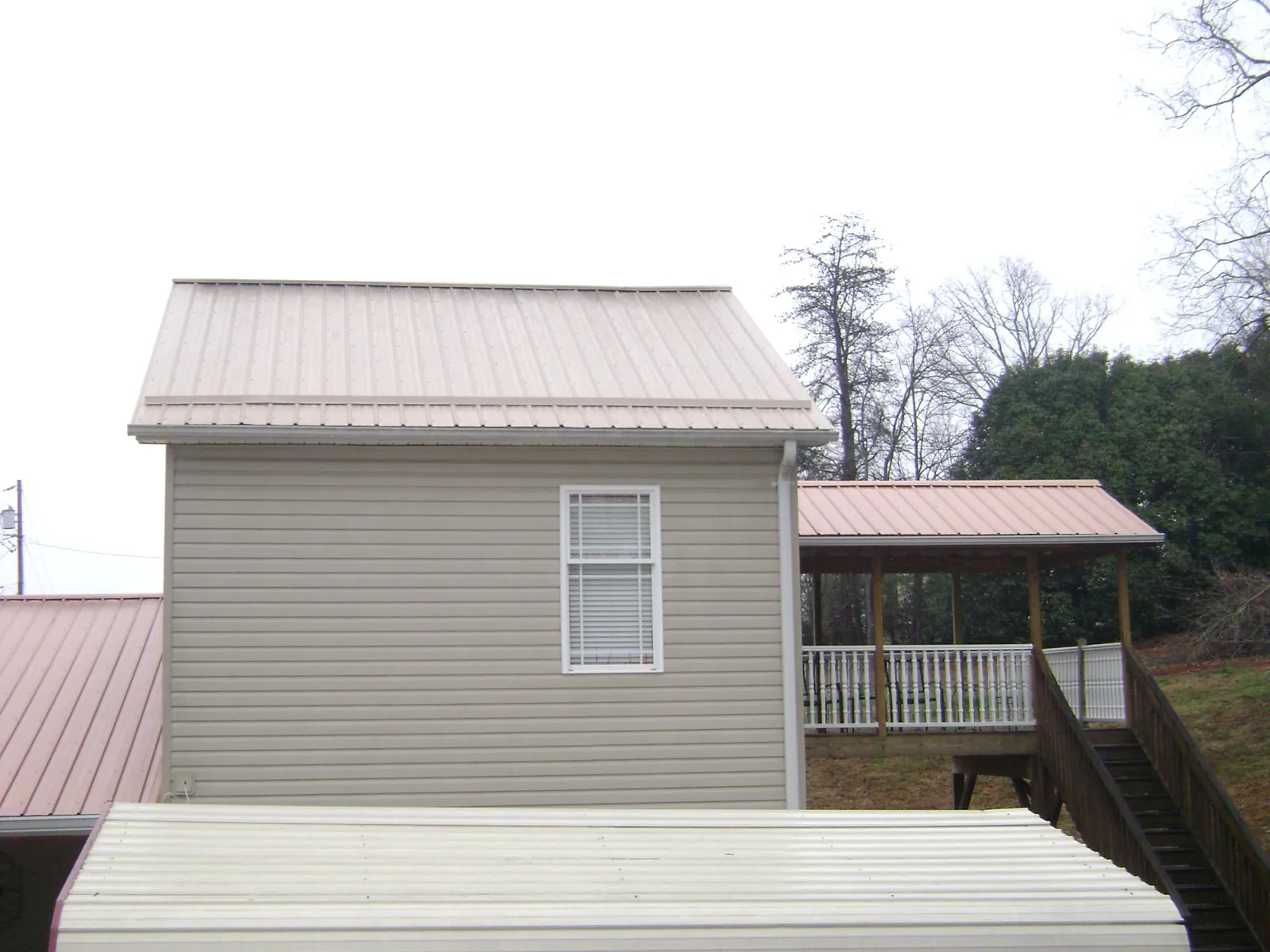 Tan metal roofs on a two story addition and attached porch, from a Roof Replacement job in Mosier